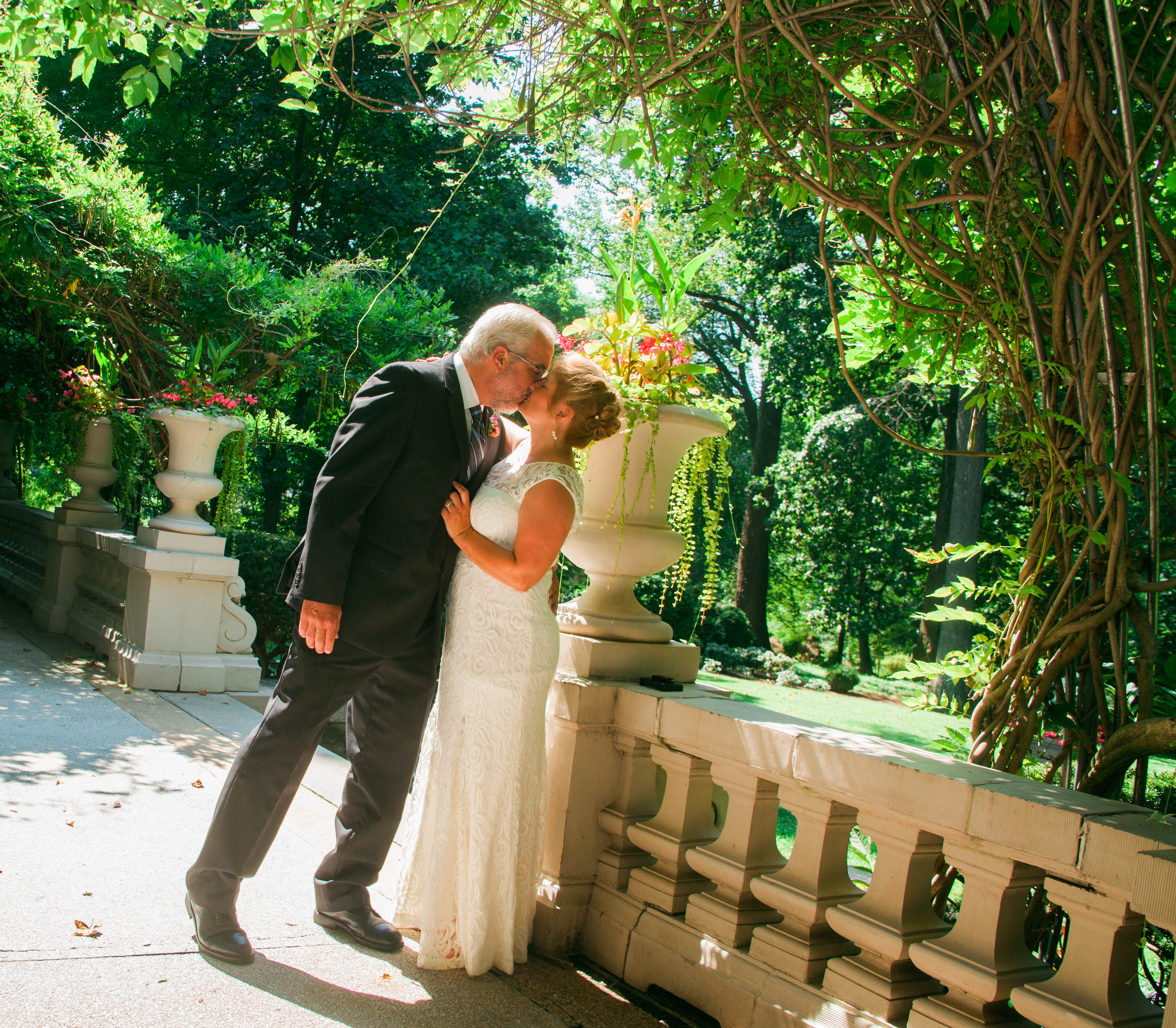 a bride and a groom stand kissing underneath greenery at the Liriodendron Mansion in Bel Air MD