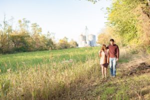 A September backyard anniversary session in Woodsboro MD. A couple walks together beside a field of tall grass