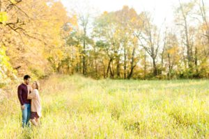 A September backyard anniversary session in Woodsboro MD. A couple stands smiling and looking at each other lovingly in a field of tall grass 