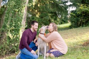 A September backyard anniversary session in Woodsboro MD. A couple sits with their dog laughing and playing