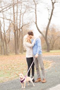 Cozy Autumn Engagement Session at Rockburn Branch Park in Elkridge, MD. A couple walks their dog and kisses in the park