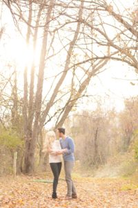 Cozy Autumn Engagement Session at Rockburn Branch Park in Elkridge, MD. A loving couple stands under the glowing sun looking at each other and smiling