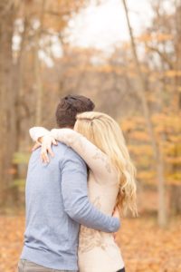 Cozy Autumn Engagement Session at Rockburn Branch Park in Elkridge, MD. A loving couple stands in an emotional embrace with golden fall leaves in the background