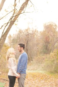 Cozy Autumn Engagement Session at Rockburn Branch Park in Elkridge, MD. A loving couple stands under the dreamy sun looking at each other and smiling
