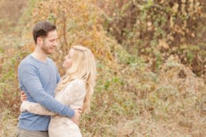 Cozy Autumn Engagement Session at Rockburn Branch Park in Elkridge, MD. A loving couple stands in sweet embrace with golden fall leaves in the background