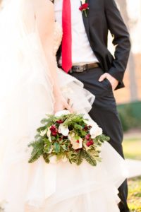A young bride and groom stand together holding a holiday bouquet at the Liriodendron Mansion in Bel Air Maryland for her winter wedding