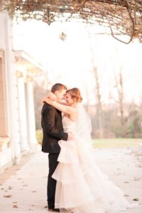 a young bride and groom share their first dance under the wisteria on the back porch of the Liriodendron Mansion in Bel Air Maryland for a Christmas Winter Wedding