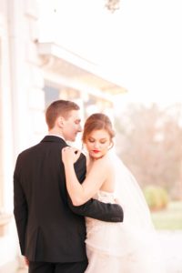 a young bride and groom share a quiet moment during their first dance under the wisteria on the back porch of the Liriodendron Mansion in Bel Air Maryland for a Christmas Winter Wedding