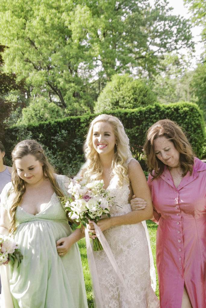 Bride walks down the aisle with her mother and maid of honor in a summer garden wedding Airlie in Warrenton Virginia