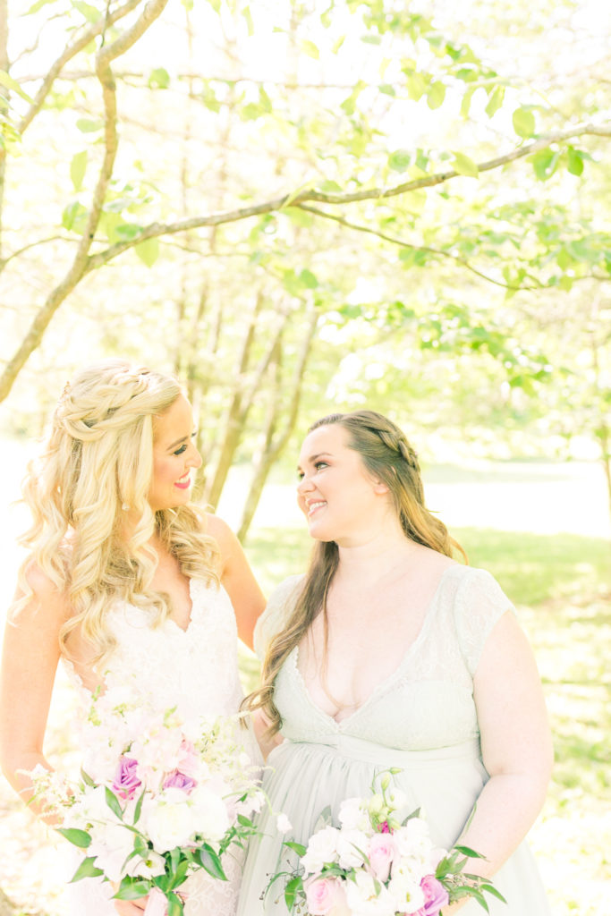 Bride and Maid of Honor smile and stand in the butterfly garden in a summer garden wedding Airlie in Warrenton Virginia