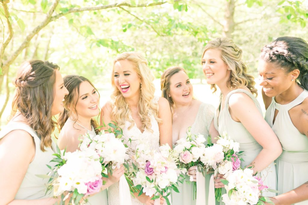 Bride and Bridesmaids laugh together in their mint green dresses at a summer garden wedding Airlie in Warrenton Virginia