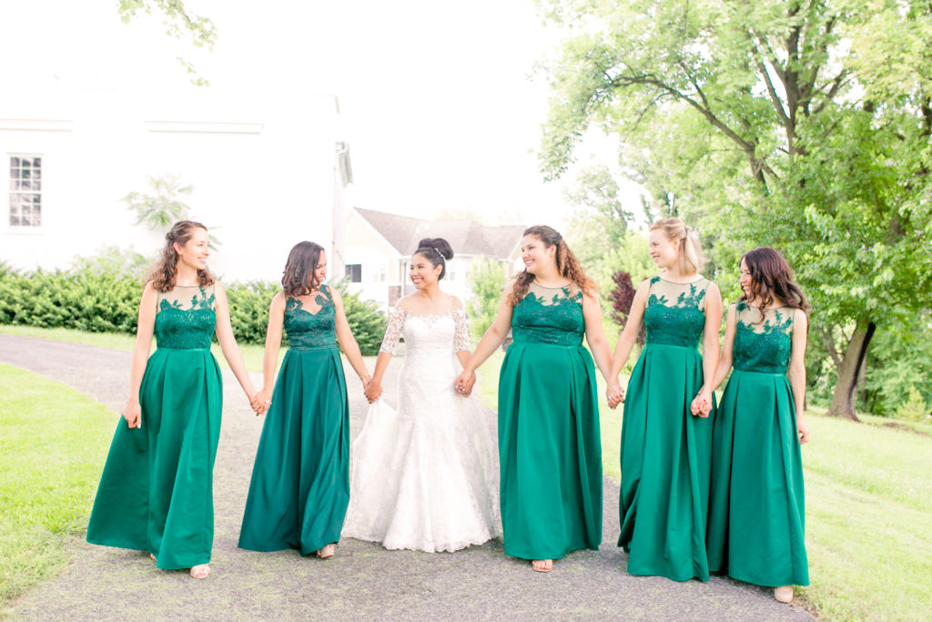 Bride and Bridesmaids walking together laughing and smiling for portraits in a summer Frederick Maryland Wedding with emerald green dresses