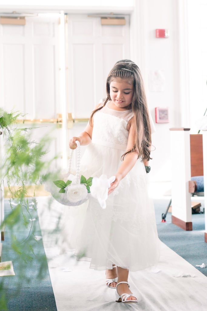 a flower girl walks down the aisle for a latino wedding in the summer in frederick maryland wedding at the Seventh Day Adventist Church