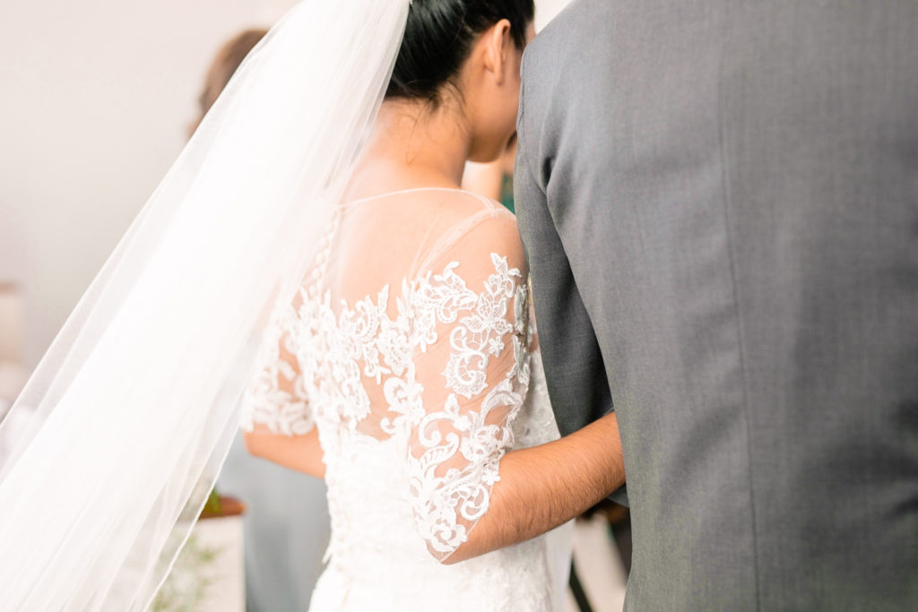 A closeup of the Bride holding onto her father as he walks her down the aisle for a latino wedding in the summer in frederick maryland wedding at the Seventh Day Adventist Church
