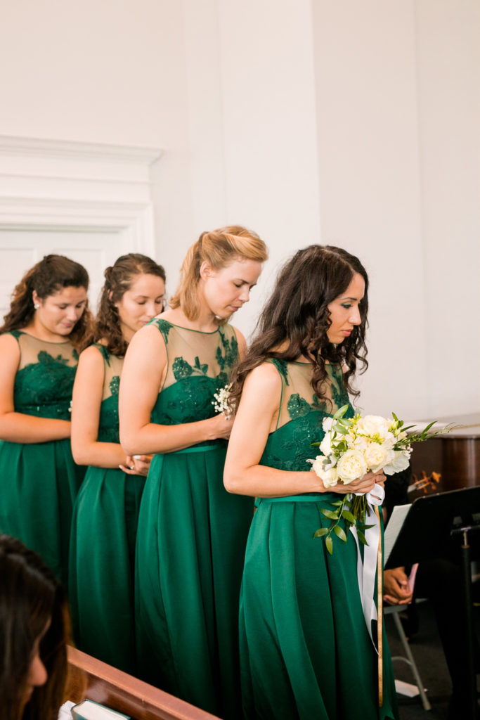 The Bridesmaids stand together in their emerald green dresses praying The Bride and Groom stand together for their ceremony in a latino wedding in the summer in frederick maryland wedding at the Seventh Day Adventist Church