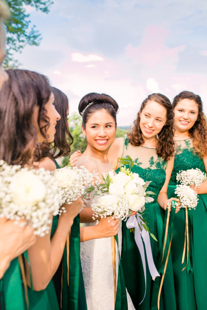 Bride and Bridesmaids stand together laughing and smiling in emerald green dresses in a summer Frederick Maryland Wedding at Prospect Hall Mansion 