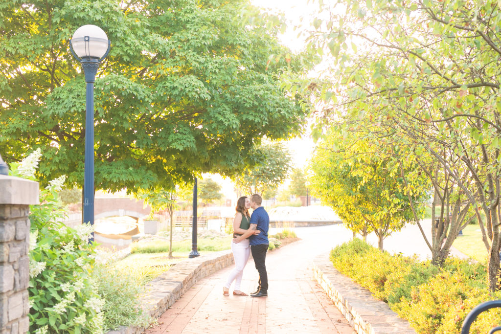 downtown Frederick sunrise summer engagement session with a couple kissing underneath the trees